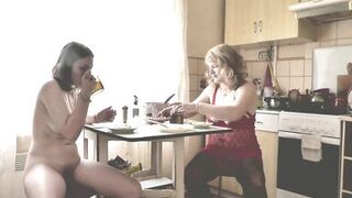 Adult woman blonde in transparent negligee and beautiful cute brunette naked girl cooks in kitchen. Lesbians. Natural tits Pussy